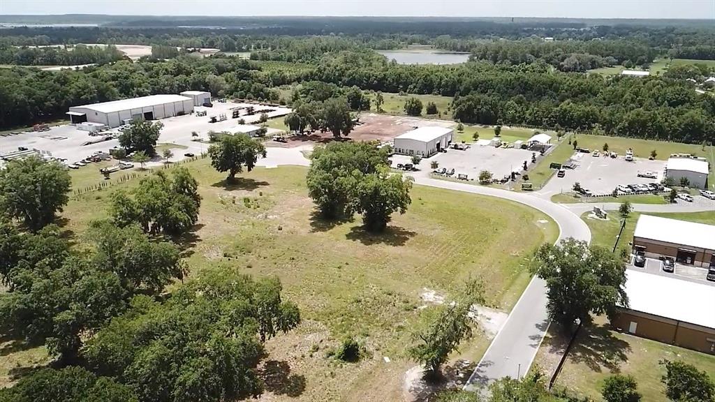 An aerial view shows several industrial buildings surrounded by trees, grassy fields, and paved lots — 1080 DUCK BOX ROAD, UMATILLA, FL