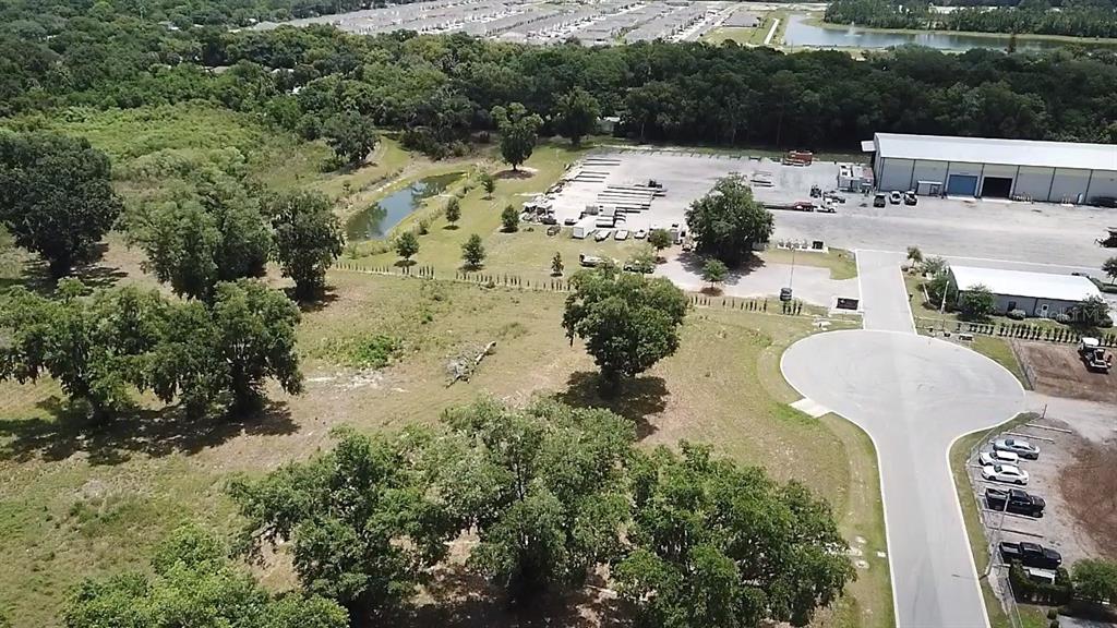 An aerial view shows a vacant grassy lot adjacent to a warehouse and paved cul-de-sac — 1080 DUCK BOX ROAD, UMATILLA, FL