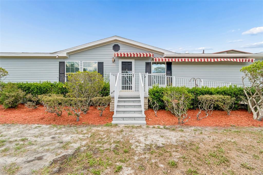 A single-story house with light gray siding, a front porch, and a wheelchair ramp — 3724 TACK DRIVE, WESLEY CHAPEL, FL