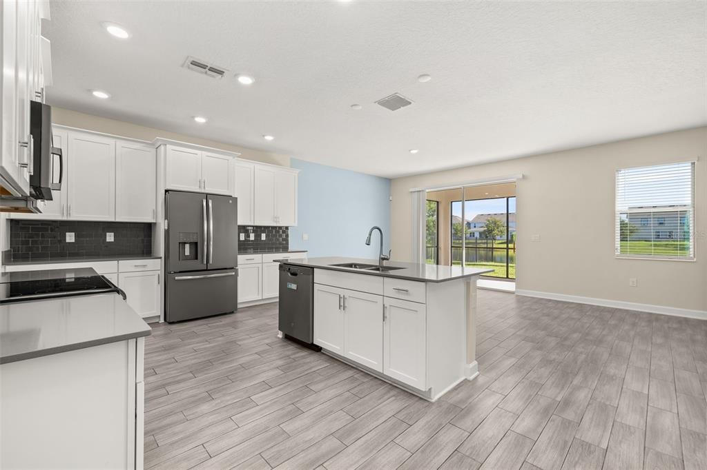 A kitchen with white cabinets, a gray island, and tile flooring overlooks a backyard pond — 4935 CHASE COURT, ST CLOUD, FL
