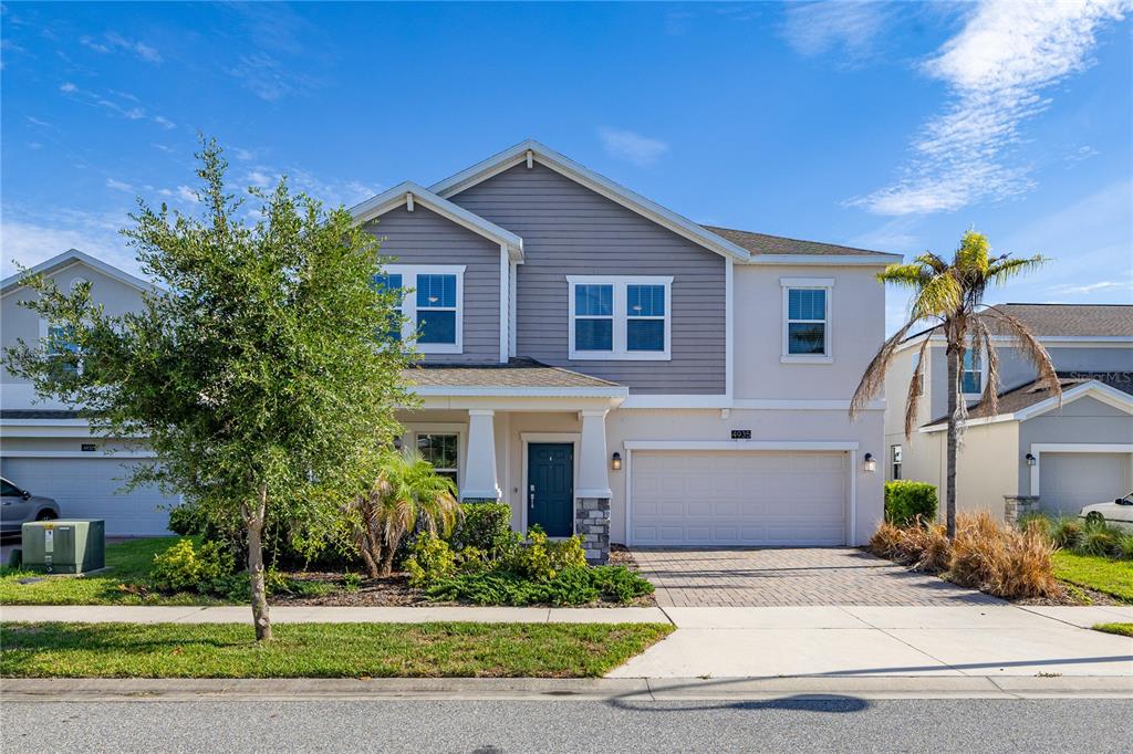 A two-story suburban house features a gray-sided upper level, a beige lower level, and a garage — 4935 CHASE COURT, ST CLOUD, FL