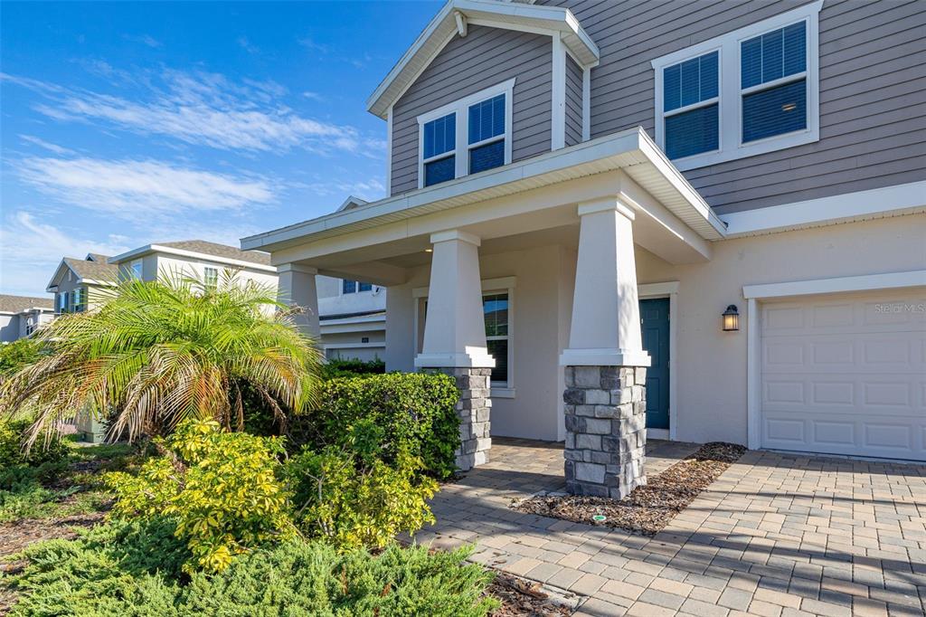 A two-story house exterior features a stone-based porch, gray siding, and a paved driveway — 4935 CHASE COURT, ST CLOUD, FL