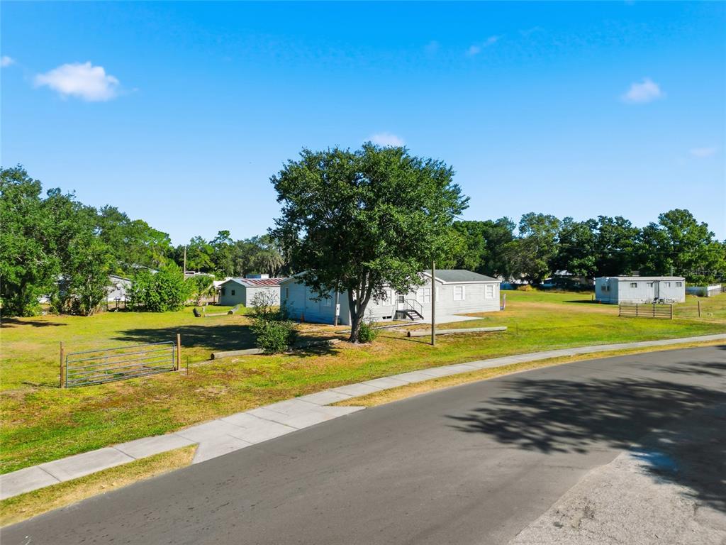 A light-colored mobile home sits on a grassy lot with a large tree and fence — 12422 BALM RIVERVIEW ROAD, RIVERVIEW, FL