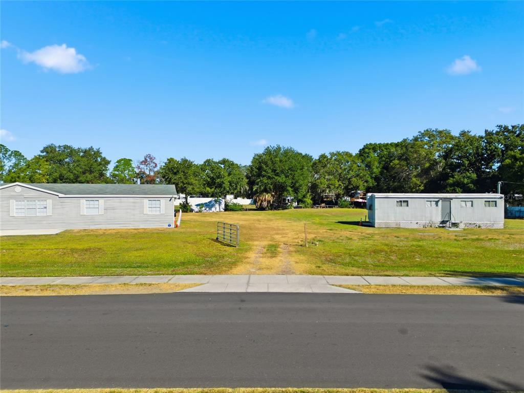 An empty grassy lot sits between two manufactured homes along a paved street — 12422 BALM RIVERVIEW ROAD, RIVERVIEW, FL