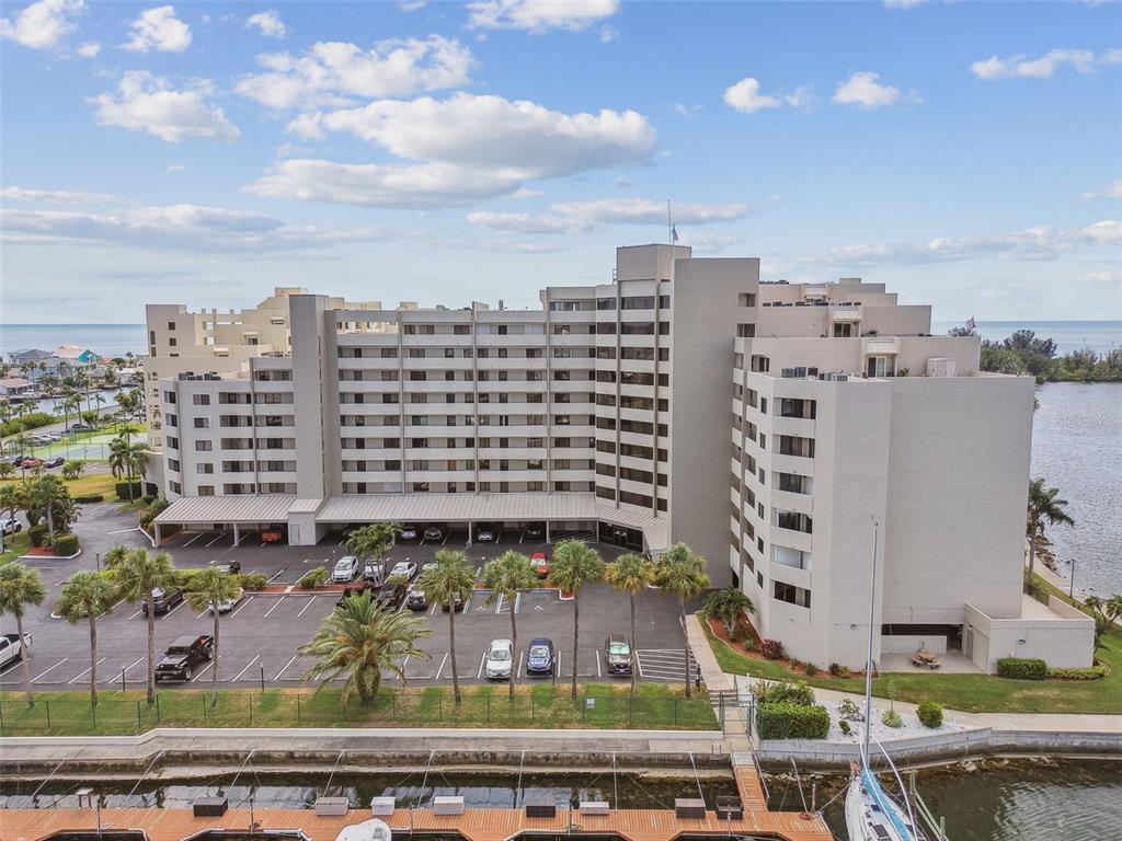 An aerial view shows a large multi-story apartment building with a parking lot and tennis court — 6035 SEA RANCH DRIVE UNIT 210, HUDSON, FL