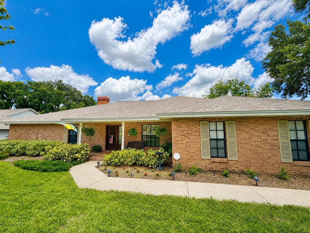 A single-story brick house with a shingled roof, a concrete walkway, and green landscaping — 411 SUMMIT CHASE DRIVE, VALRICO, FL