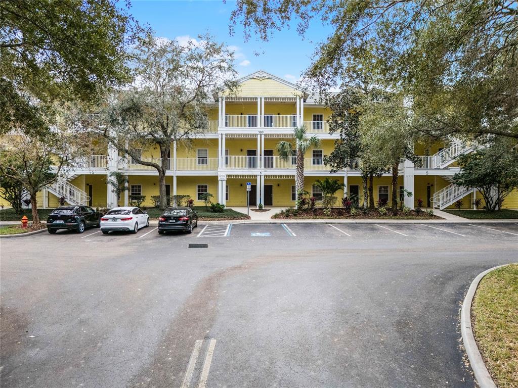 A three-story yellow apartment building with white balconies and a parking lot in front — 312 LUCAYA LOOP, DAVENPORT, FL