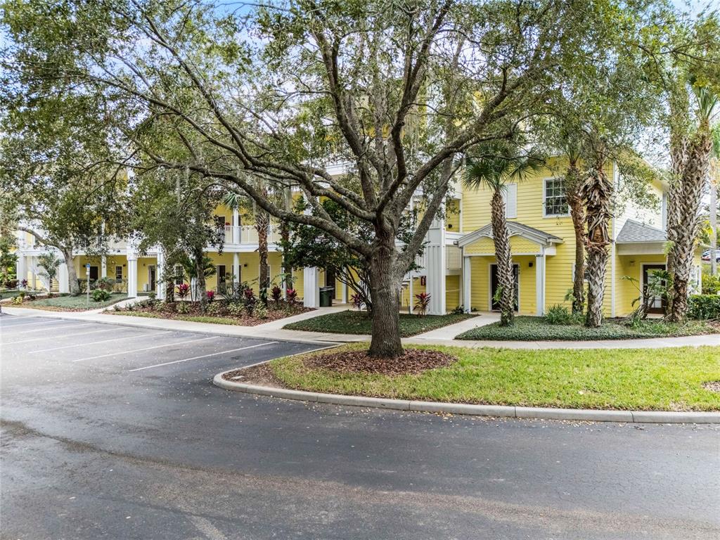 A yellow multi-story apartment building with a parking lot and large trees in front — 312 LUCAYA LOOP, DAVENPORT, FL
