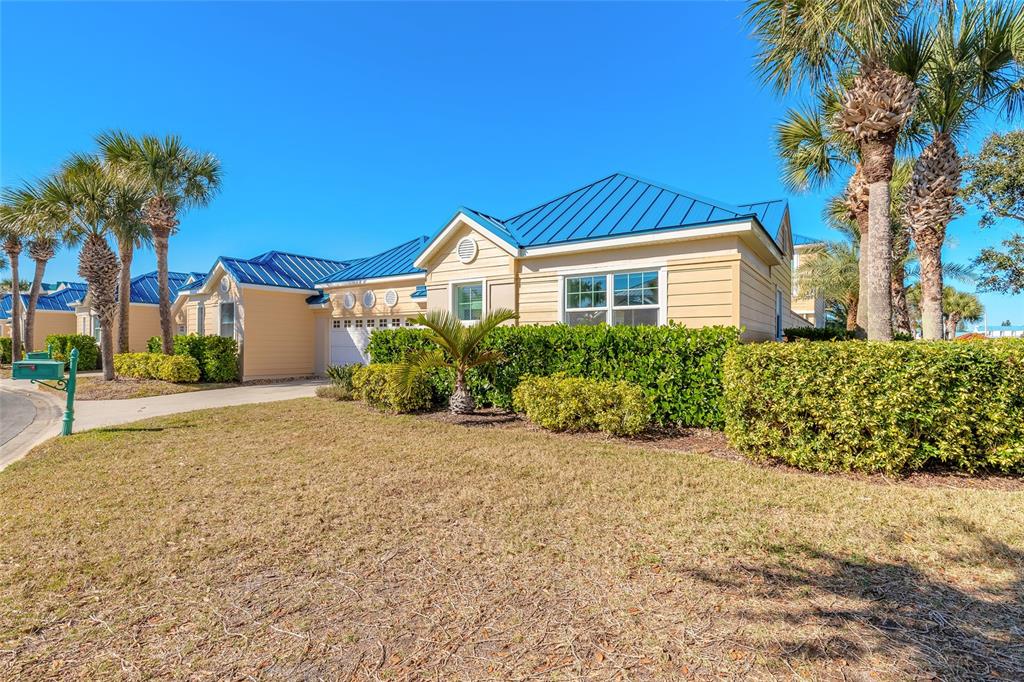 A single-story house with a blue metal roof and tan siding sits behind a hedge — 4641 RIVERWALK VILLAGE COURT, PONCE INLET, FL