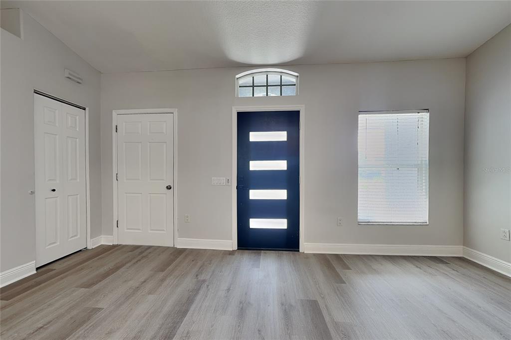 A room with light gray walls, wood-look flooring, a dark blue front door, and two closets — 4840 TIMBER WAY, ZEPHYRHILLS, FL