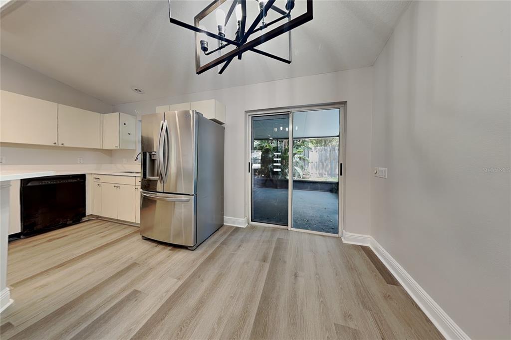 A kitchen with light-colored cabinets, stainless steel appliances, and a sliding glass door to a patio — 4840 TIMBER WAY, ZEPHYRHILLS, FL