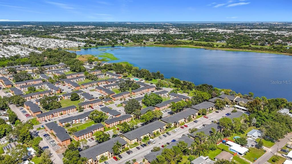 An aerial view shows a large apartment complex situated next to a lake — 10199 SAILWINDS BOULEVARD S UNIT 201, LARGO, FL