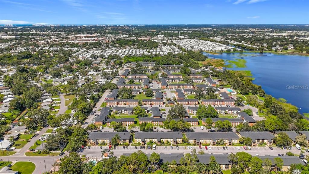 An aerial view shows a multi-building apartment complex situated next to a large lake — 10199 SAILWINDS BOULEVARD S UNIT 201, LARGO, FL