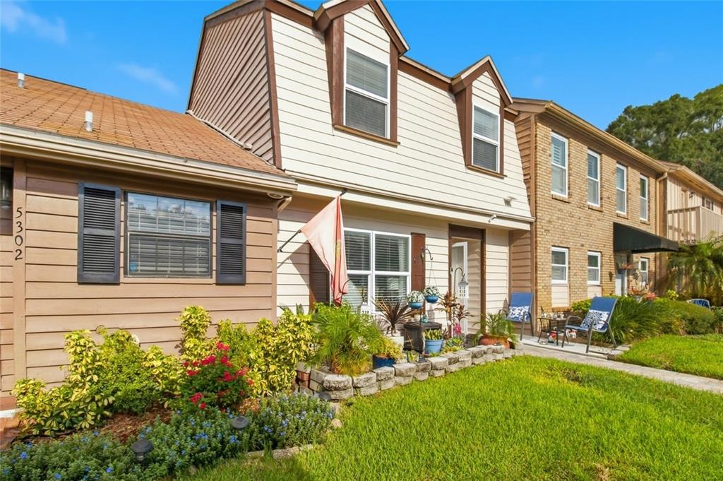 A two-story townhouse with beige siding, a brick facade, and a landscaped front yard — 5304 BRADBURY COURT, TAMPA, FL
