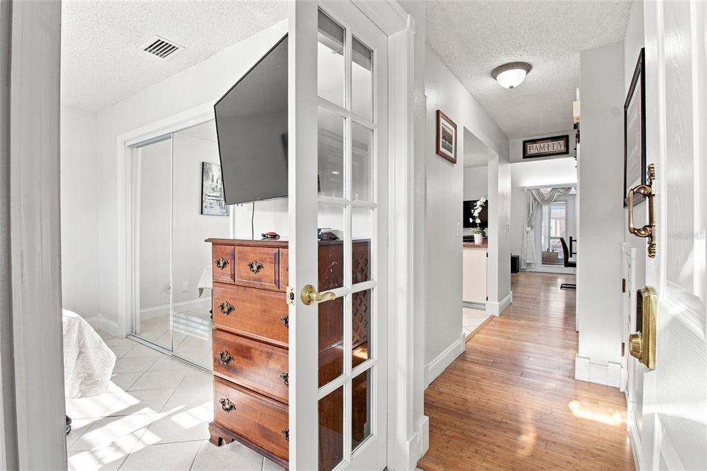 A hallway with wood flooring leads to a room with a dresser and glass doors — 5304 BRADBURY COURT, TAMPA, FL