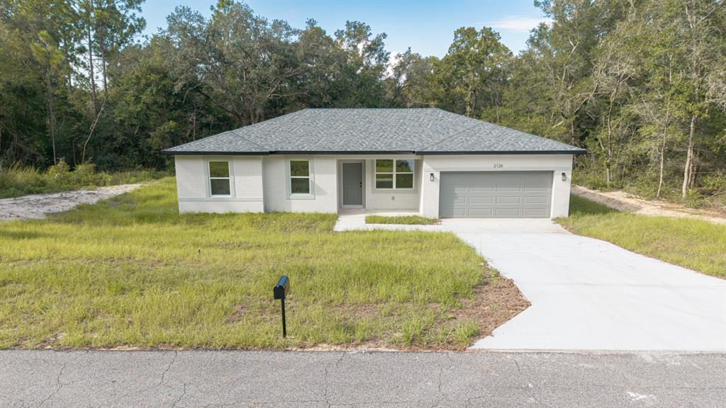 A single-story house with a gray roof, light-colored stucco exterior, and a two-car garage — 2126 W CHARLENE PLACE, DUNNELLON, FL