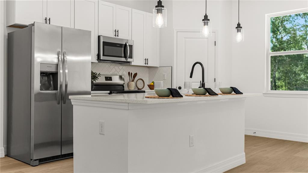 A modern kitchen features white cabinets, stainless steel appliances, and a central island with seating — 2126 W CHARLENE PLACE, DUNNELLON, FL