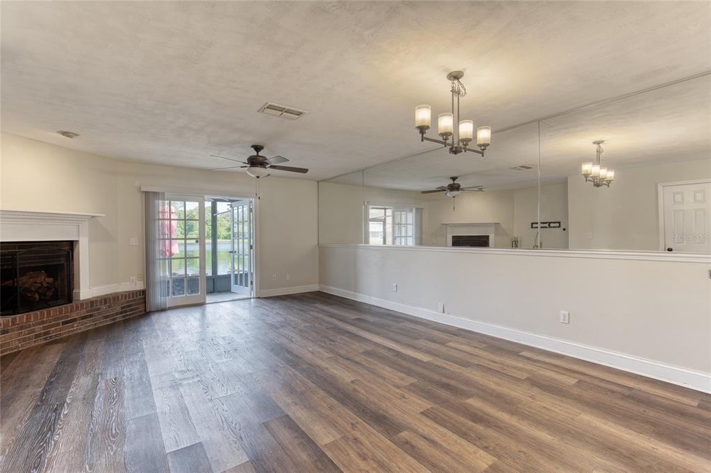 A living and dining area with wood floors, a fireplace, and a large mirrored wall — 210 LEMON TREE LANE UNIT 9, ORMOND BEACH, FL