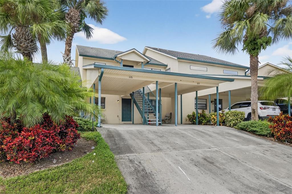 A two-story residential building features a covered carport, an exterior staircase, and palm trees — 620 YARDARM DRIVE UNIT 10, APOLLO BEACH, FL