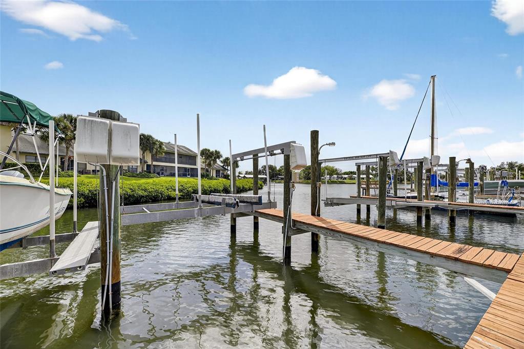 A wooden boat dock with a lift extends into a canal near residential buildings — 620 YARDARM DRIVE UNIT 10, APOLLO BEACH, FL