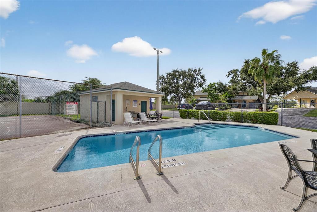 An outdoor swimming pool with a metal ladder and a small cabana in the background — 620 YARDARM DRIVE UNIT 10, APOLLO BEACH, FL