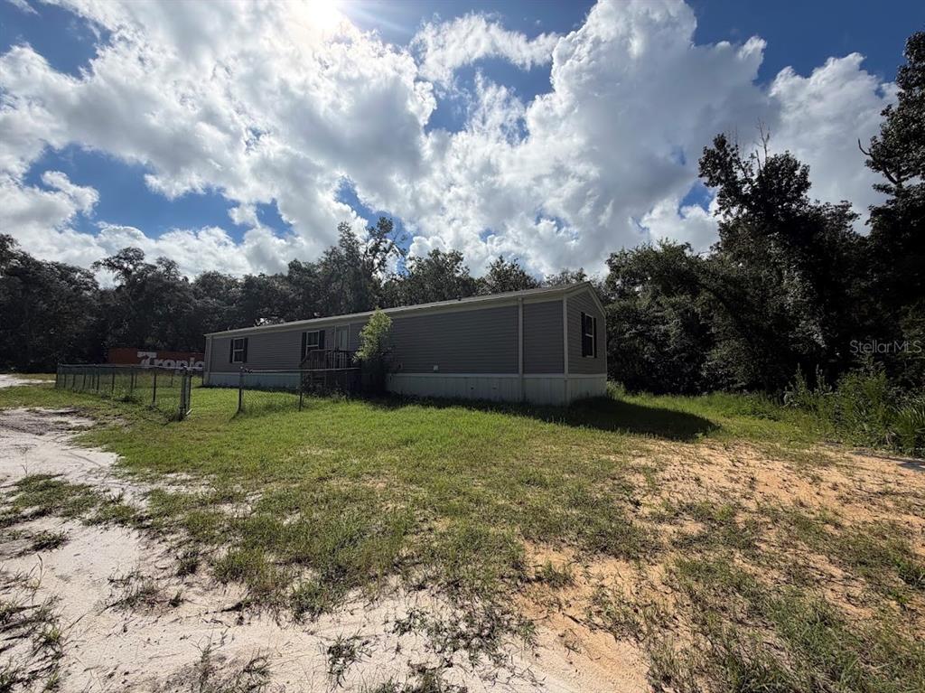 A single-story manufactured home with gray siding sits on a grassy lot under a cloudy sky — 16456 NE 35TH AVENUE ROAD, CITRA, FL