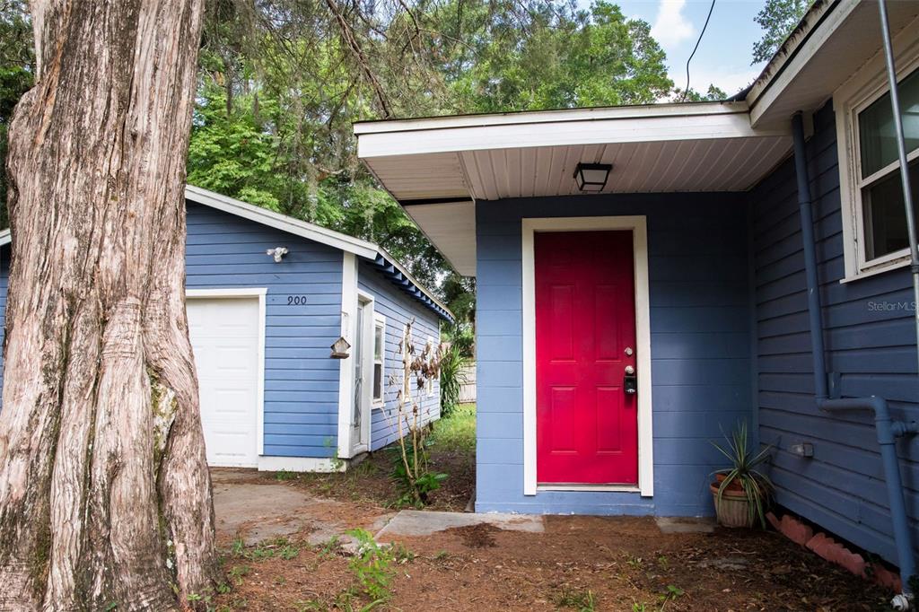 A blue house with a bright red door stands next to a detached garage — 900 KENTUCKY BOULEVARD, EUSTIS, FL