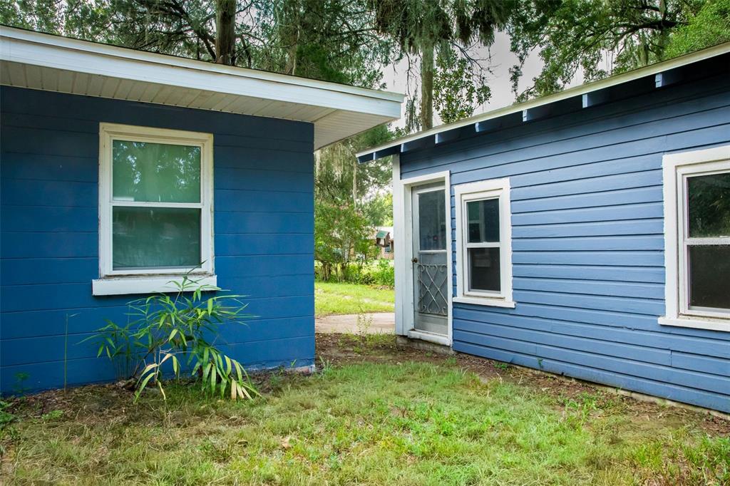 The exterior of two blue-sided buildings with white trim and windows separated by a walkway — 900 KENTUCKY BOULEVARD, EUSTIS, FL