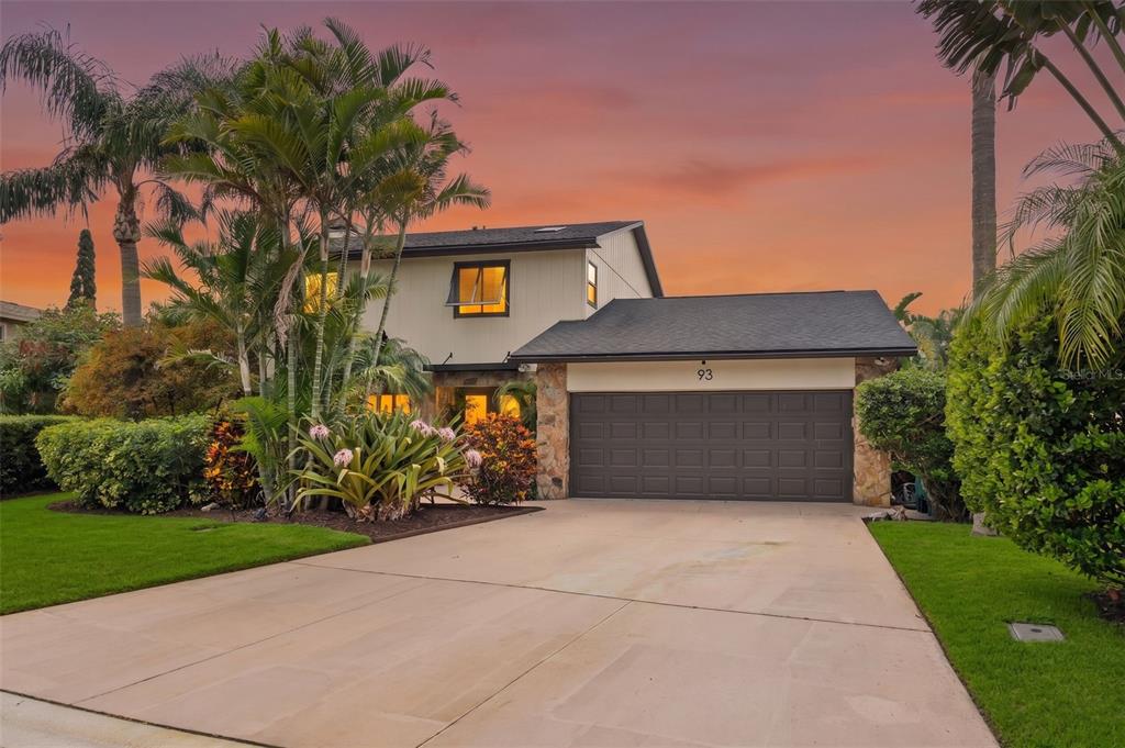 A two-story house with a garage, palm trees, and landscaping at sunset — 93 S CANAL DRIVE, PALM HARBOR, FL