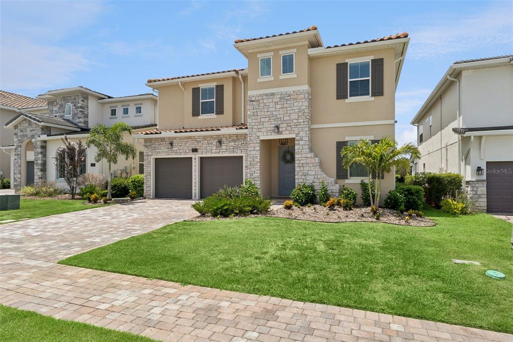 A two-story suburban house with a stone facade, two-car garage, and a manicured front lawn — 16111 VOLTERRA POINT, MONTVERDE, FL