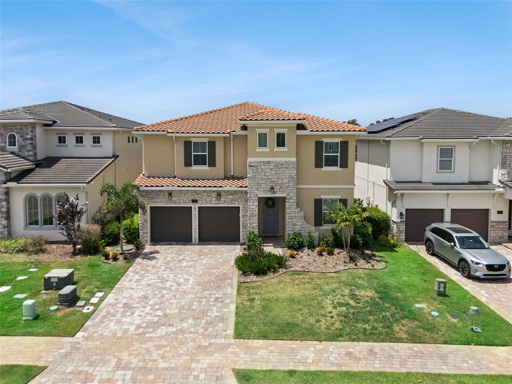 A two-story suburban house with a stone facade, tile roof, and a paved driveway — 16111 VOLTERRA POINT, MONTVERDE, FL