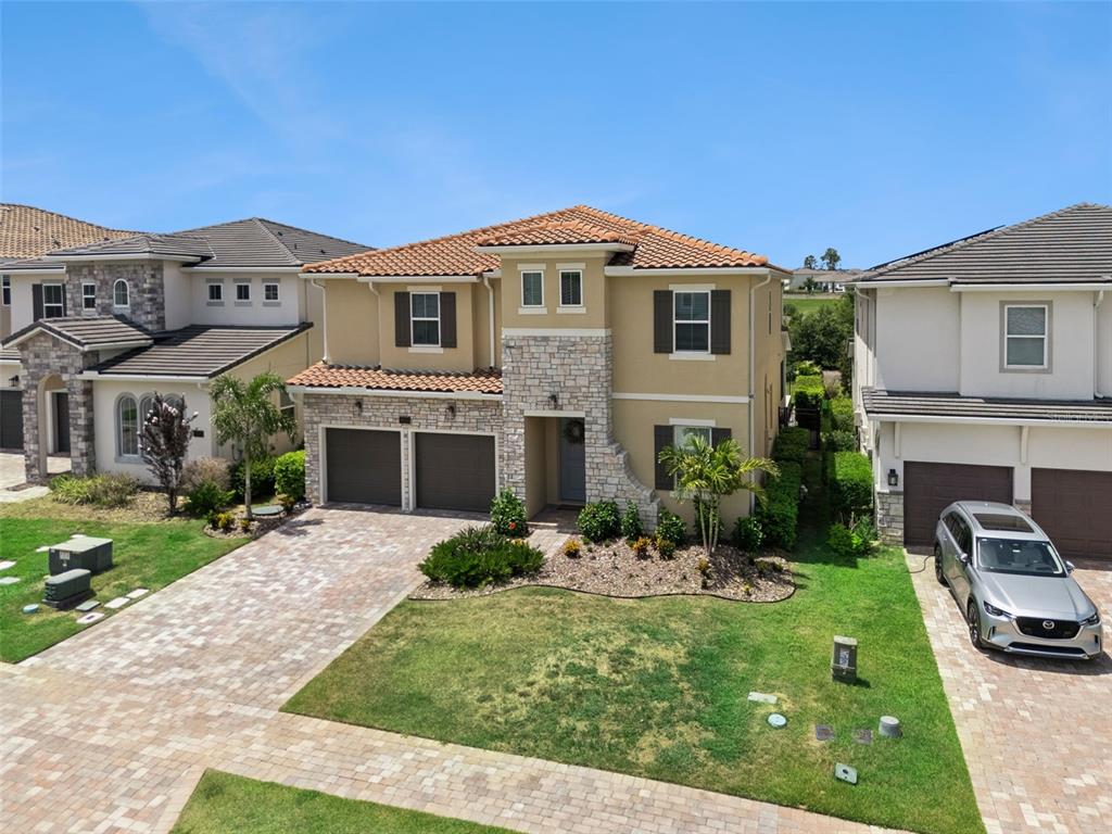 A two-story house with a stone facade, tile roof, and a paved driveway — 16111 VOLTERRA POINT, MONTVERDE, FL