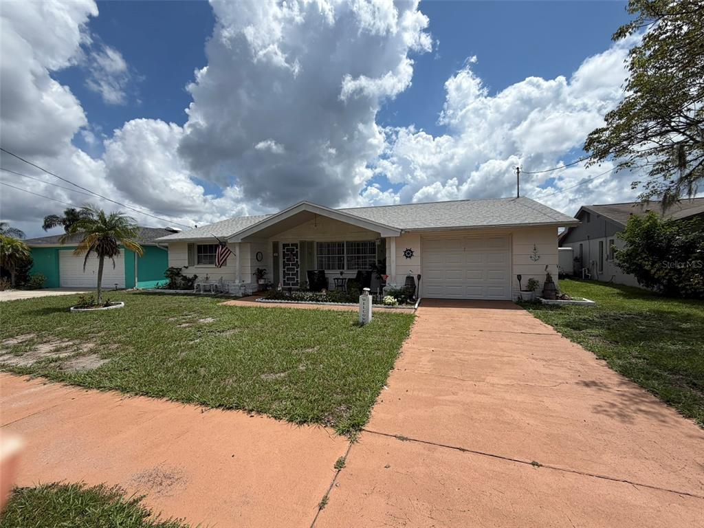 A single-story house with a beige exterior, a white garage door, and a concrete driveway — 1332 FLOTILLA DRIVE, HOLIDAY, FL