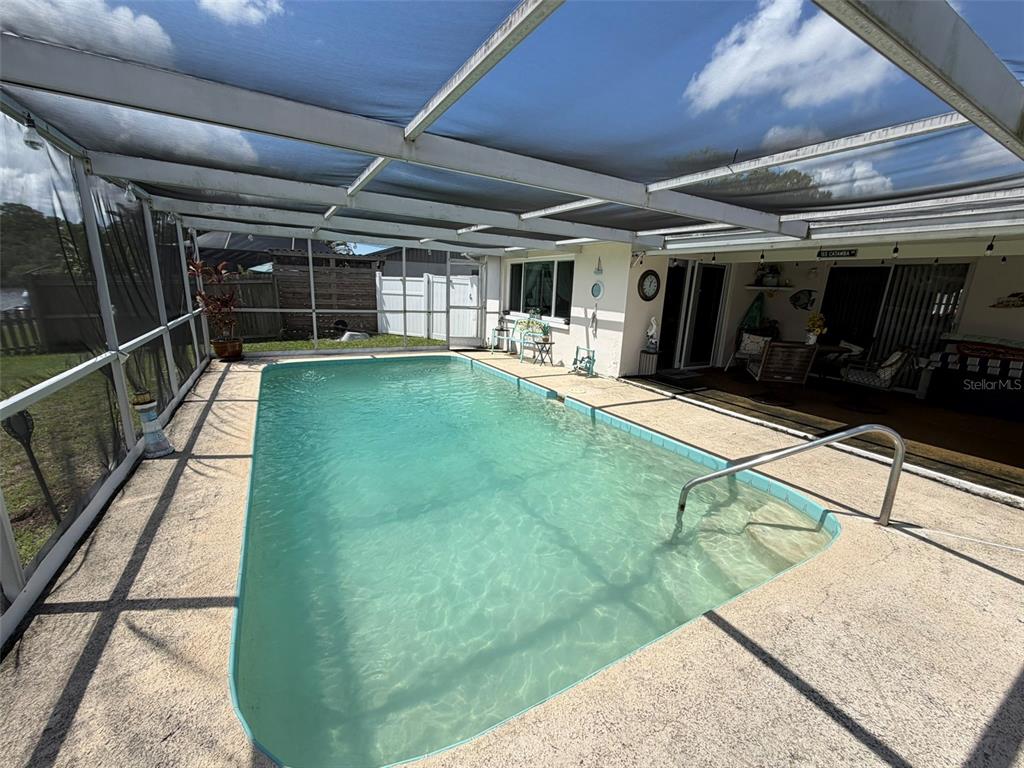 A screened-in swimming pool with a concrete deck and a covered patio area — 1332 FLOTILLA DRIVE, HOLIDAY, FL