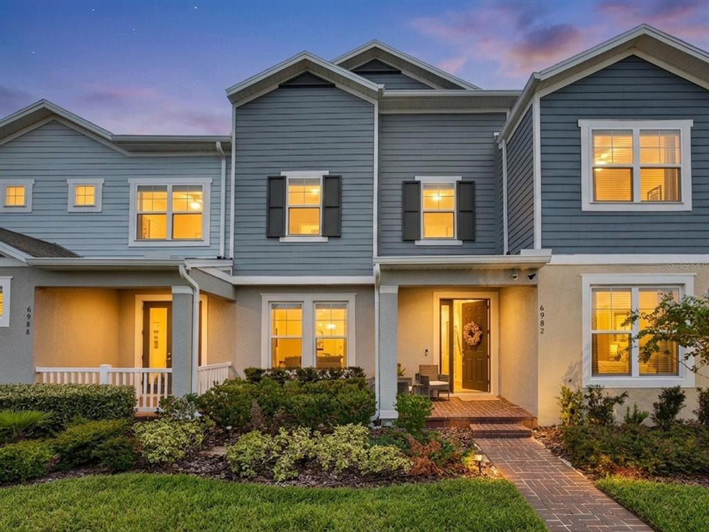 A two-story townhouse exterior features blue siding, a brick walkway, and a small front porch — 6982 TWILIGHT BAY DRIVE, WINTER GARDEN, FL