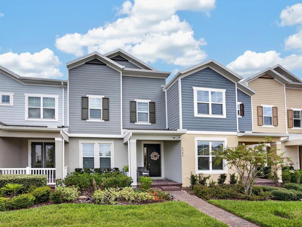 A row of multi-story townhomes with gray and tan siding and brick walkways — 6982 TWILIGHT BAY DRIVE, WINTER GARDEN, FL
