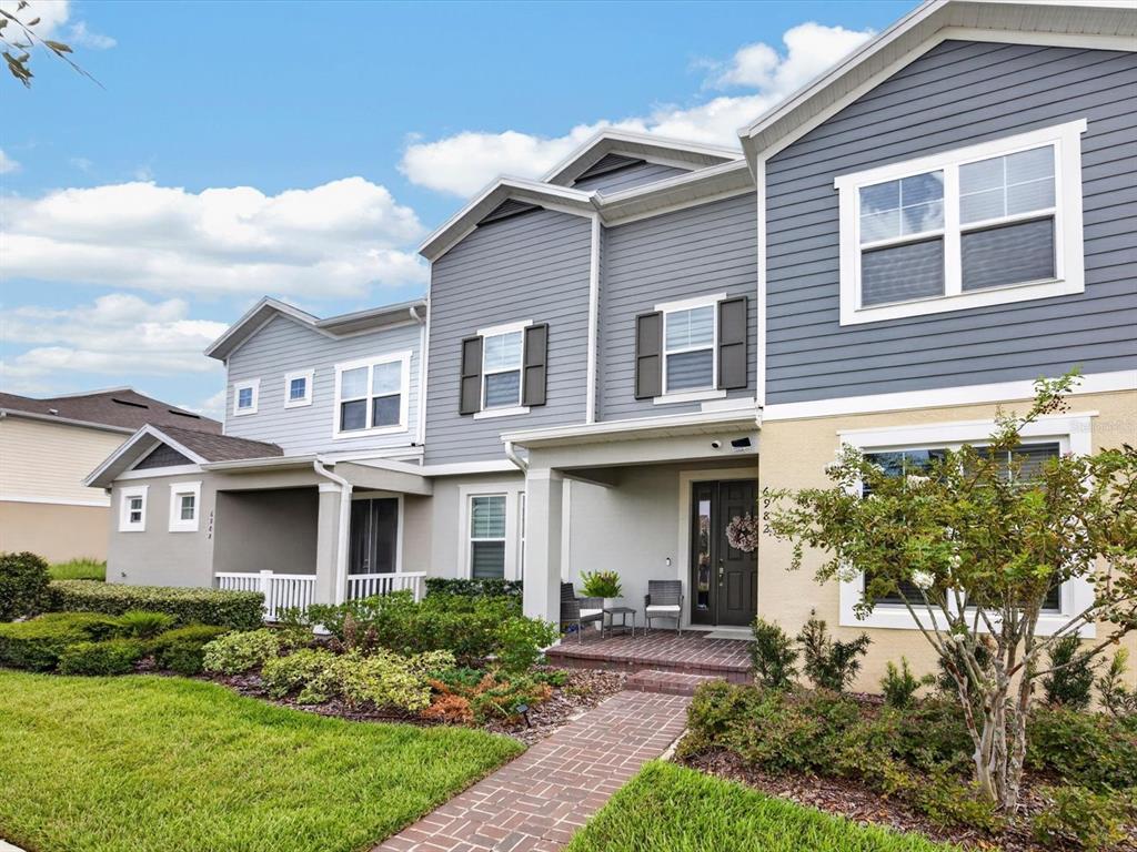 A two-story townhouse with gray siding, a brick walkway, and a landscaped front yard — 6982 TWILIGHT BAY DRIVE, WINTER GARDEN, FL