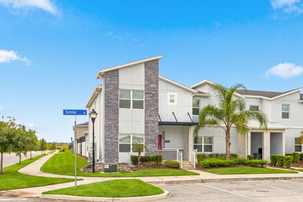 A two-story townhouse with a stone-accented facade, a covered entryway, and a palm tree — 2961 SIMILE STREET, KISSIMMEE, FL