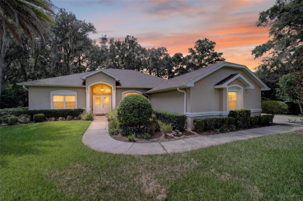 A single-story house with a beige stucco exterior, arched entryway, and a concrete walkway — 5156 NW 82ND COURT, OCALA, FL