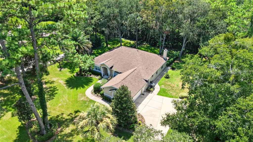 An aerial view of a single-story house with a brown roof surrounded by lush trees — 5156 NW 82ND COURT, OCALA, FL