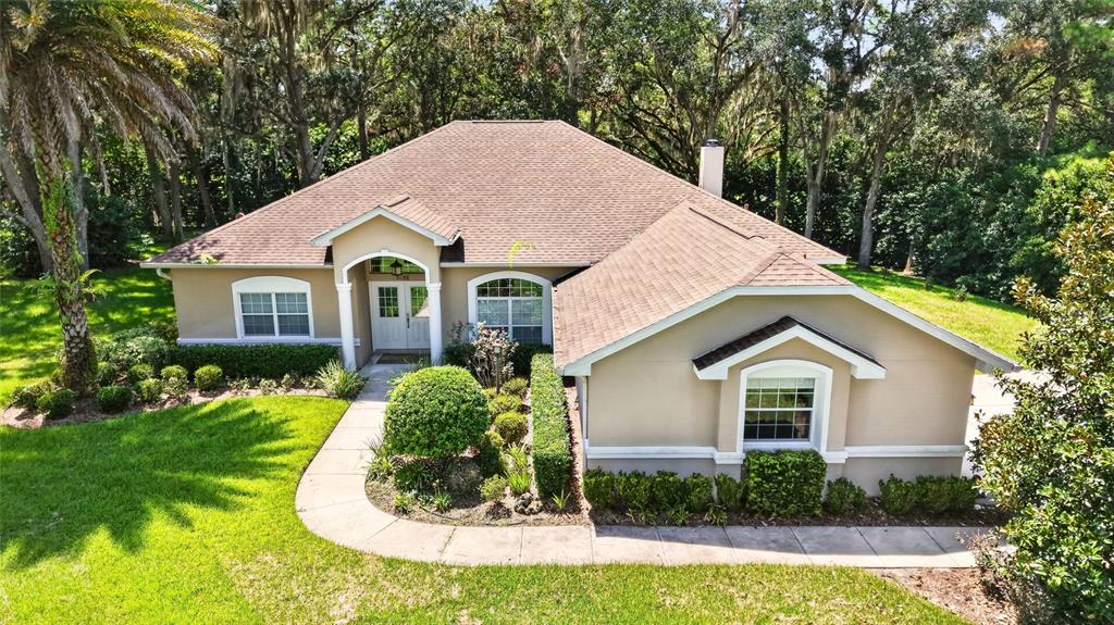 An aerial view of a single-story tan house with a brown shingled roof and landscaping — 5156 NW 82ND COURT, OCALA, FL