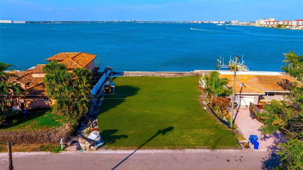 An aerial view of a vacant waterfront lot situated between two residential houses — 500 BELLE POINT DRIVE, ST PETE BEACH, FL