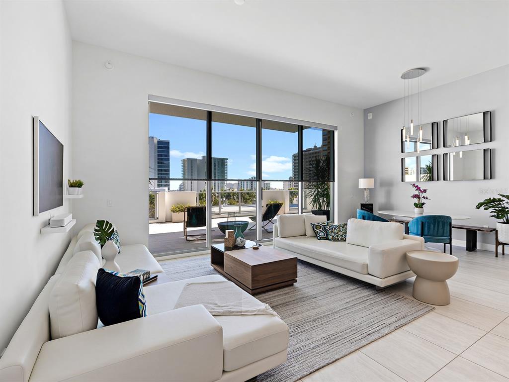 A modern living room features white sofas, a wooden coffee table, and a large balcony — 301 QUAY COMMONS UNIT 509, SARASOTA, FL