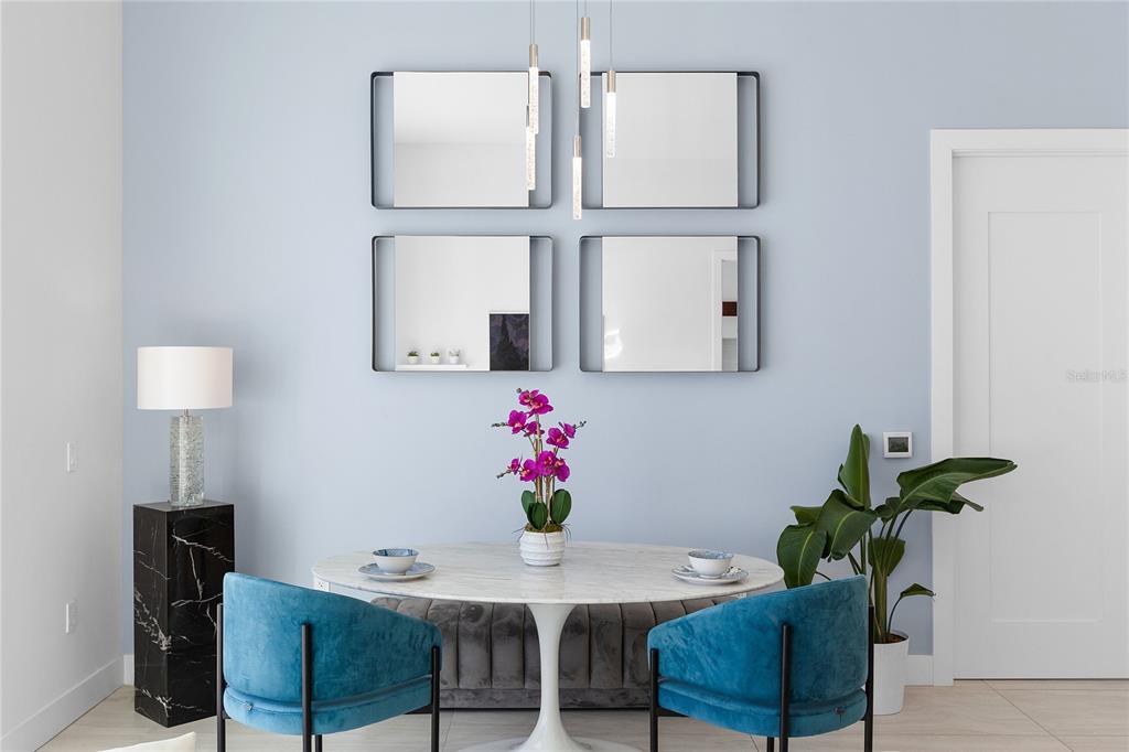 A dining area features a round marble table, blue velvet chairs, and four wall mirrors — 301 QUAY COMMONS UNIT 509, SARASOTA, FL