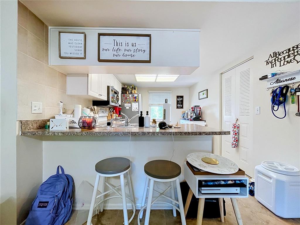 A kitchen with a breakfast bar, two stools, and decorative wall signs — 202 MEADOW LANE UNIT 50, OLDSMAR, FL