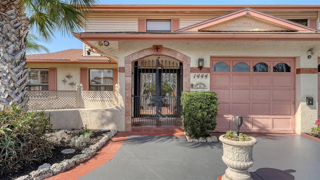The exterior of a house features a gated entryway, a garage, and a landscaped front yard — 1444 RIDGEWOOD LANE, SARASOTA, FL