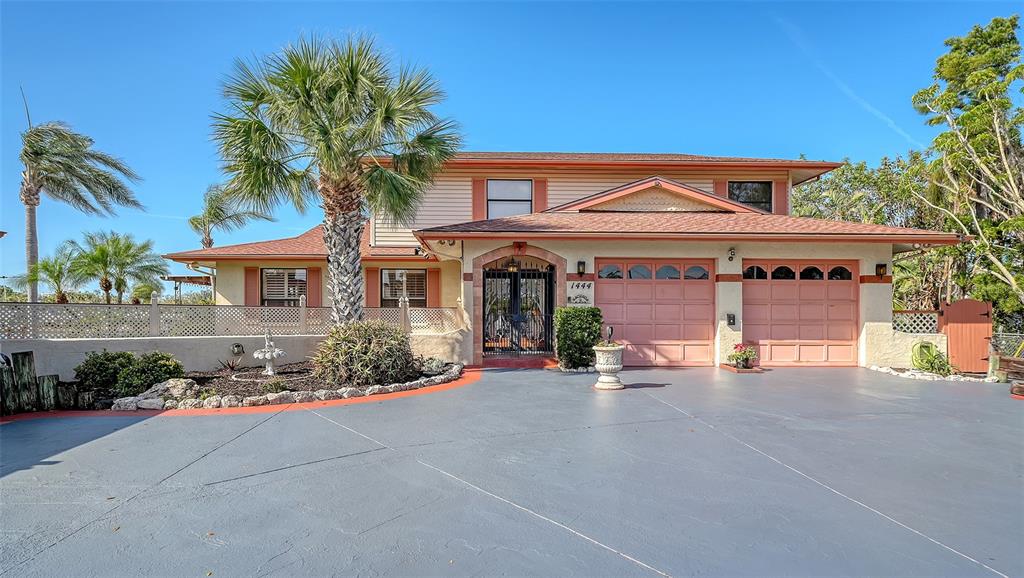 A two-story house with a blue driveway, two garage doors, and a palm tree — 1444 RIDGEWOOD LANE, SARASOTA, FL