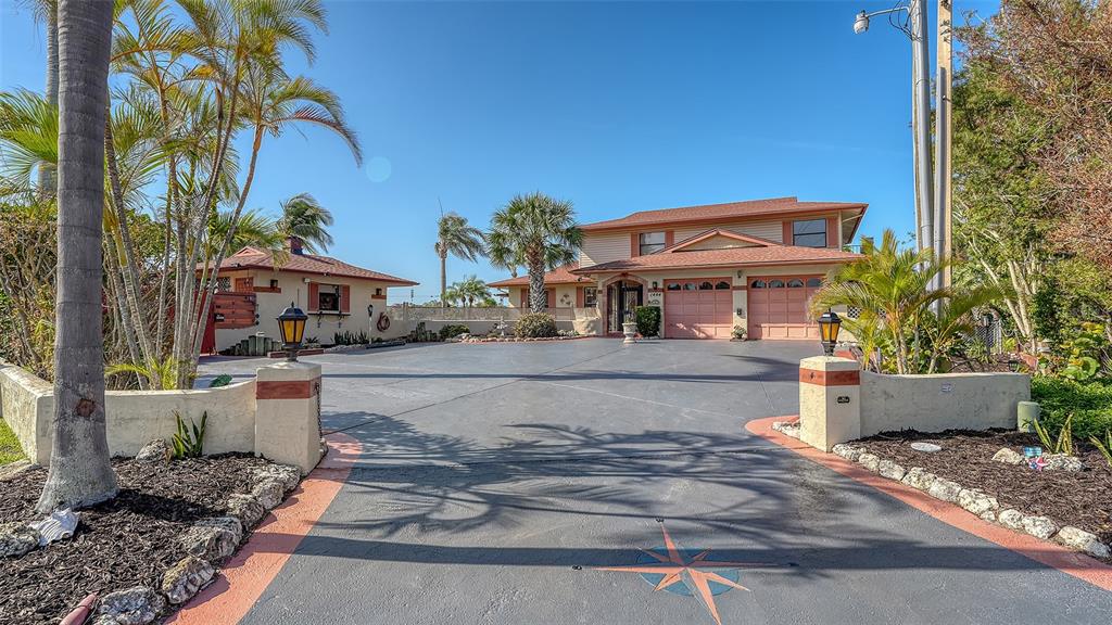 A two-story house with a large paved driveway, palm trees, and a detached garage — 1444 RIDGEWOOD LANE, SARASOTA, FL