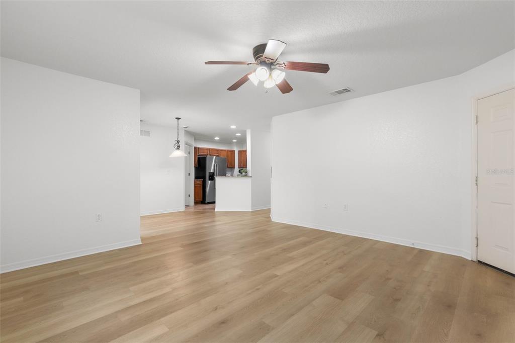 A living room with light wood-look flooring, a ceiling fan, and an open kitchen beyond — 4600 E MOODY BOULEVARD UNIT 7H, BUNNELL, FL