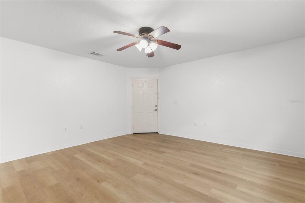An empty room features white walls, light wood-look flooring, and a ceiling fan — 4600 E MOODY BOULEVARD UNIT 7H, BUNNELL, FL